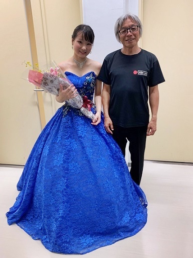 写真　ブルーの衣装で花束をもつピアニストの大竹かな子さんと三澤洋史