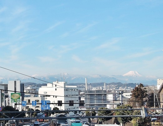 写真　歩道橋の上からみた青空に頭を突き出した富士山